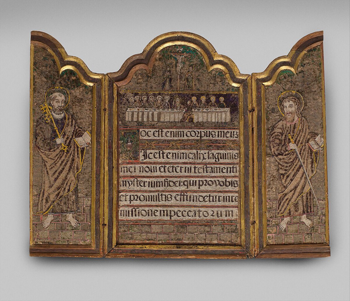 An open three-panel framed object. Standing figures occupy the side panels; a group gathered at a long table appears above several lines of lettering in the center. The surface has mottled green, brown and gold colors.